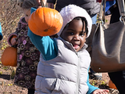 kid smiling while holding a pumpkin